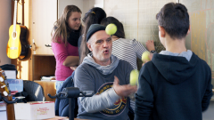 Ein Lehrer jongliert in einem Klassenraum mit Schülern