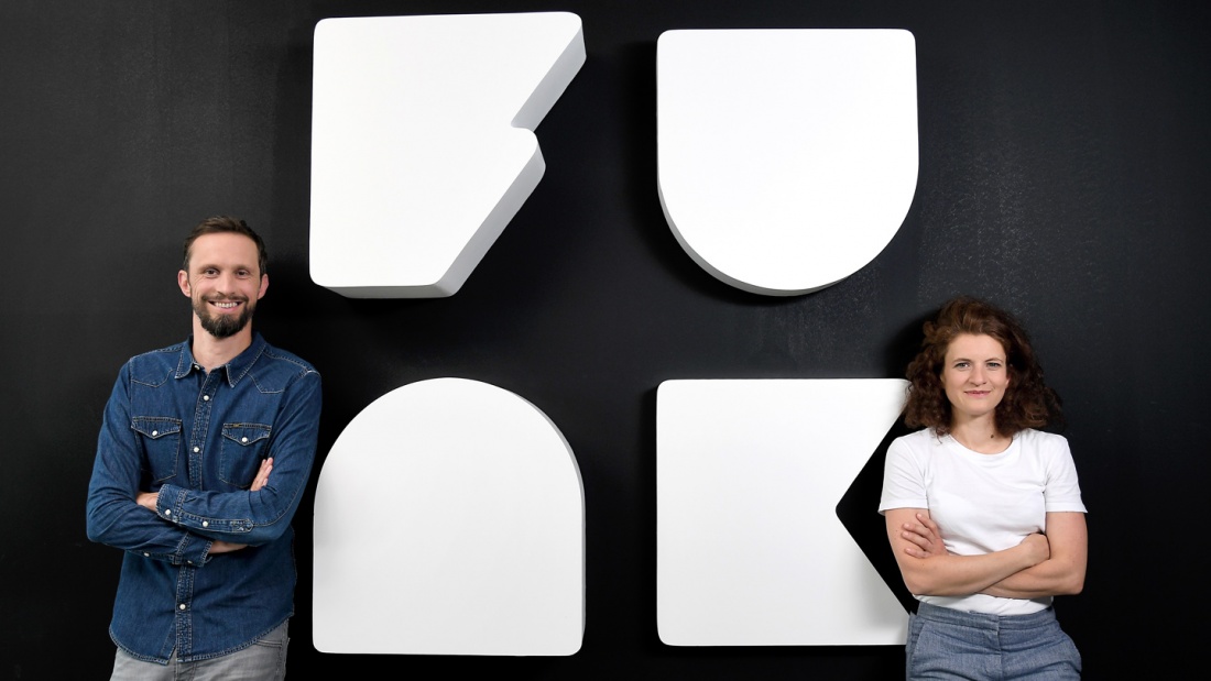 Die Geschäftsführer Florian Hager und Sophie Burkhardt stehen vor dem Logo des Content-Netzwerks funk