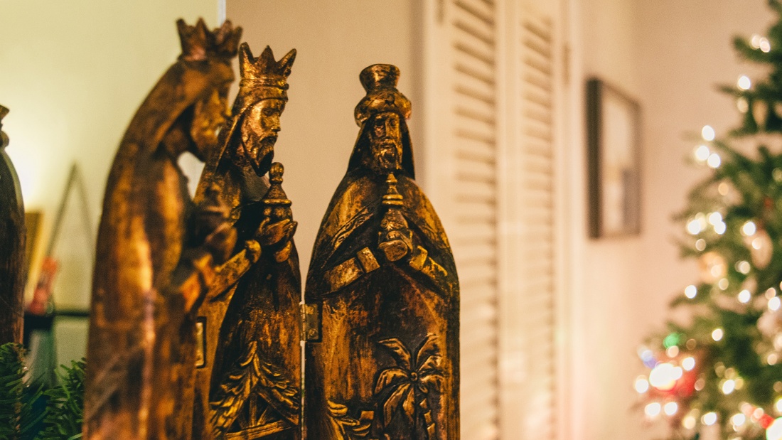 Bronzefiguren der Heiligen Drei Könige vor einem Weihnachtsbaum im Hintergrund