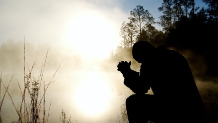 Ein Mann in den Bergen schaut in den Nebel und betet