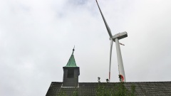 Neben einer alten Kirche in Bremerhaven steht ein Windrad.