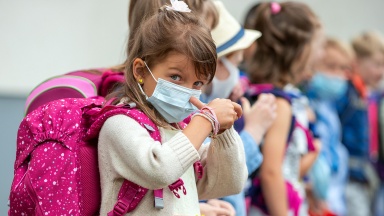 Mit Mund-Nasen-Schutz und neuem Schulranzen steht die fünfjährige Mariella-Marie nach der Einschulungsfeier auf dem Hof der Grundschule Lankow.