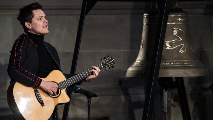 Michael Patrick Kelly steht neben der Friedensglocke und spielt einen Song in der Christuskirche Mainz