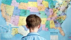 Kind steht vor einer Karte der USA.