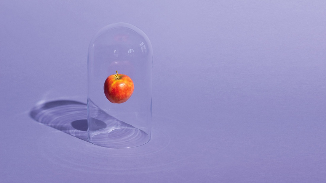 Illustration: Ein Apfel schwebt in einer Glasglocke, die auf einem lila Untergrund steht