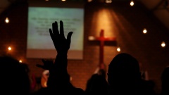 Person hebt während eines Gottesdienstes in einer Kirche eine Hand in die Luft