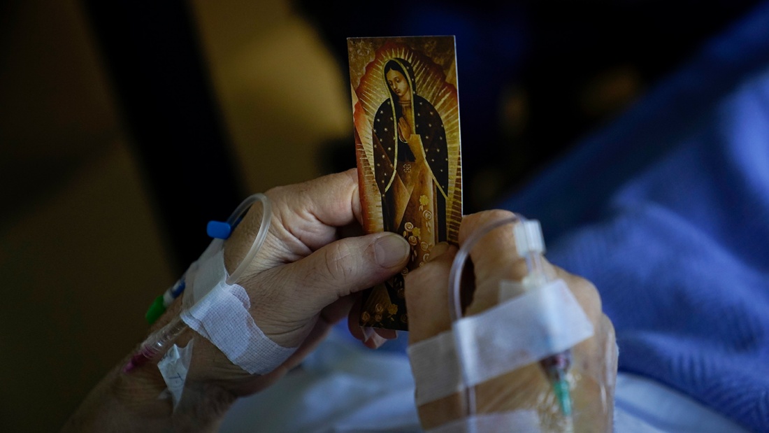 Ein Patient im Krankenhaus mit einem Gnadenbild Marias in den Händen.