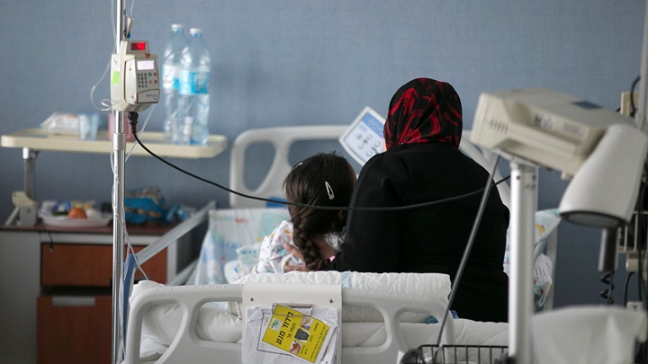 Eine syrische Mutter sitzt am Bett ihrer Tochter, die im Ziv Medical Center in Safed, Israel, behandelt wird.