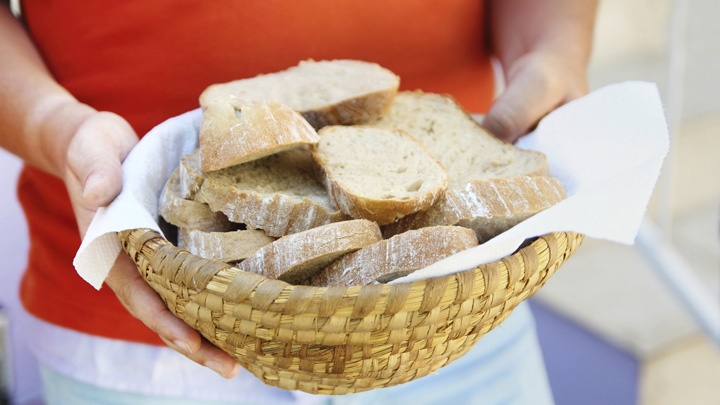 Eine Frau hält einen Korb mit Brot in den Händen.