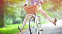 Frau streckt auf einem Fahrrad ihre Beine in die Luft.