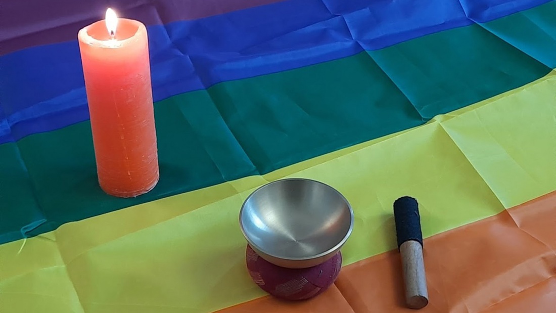 Klangschale und Kerze auf Regenbogenflagge