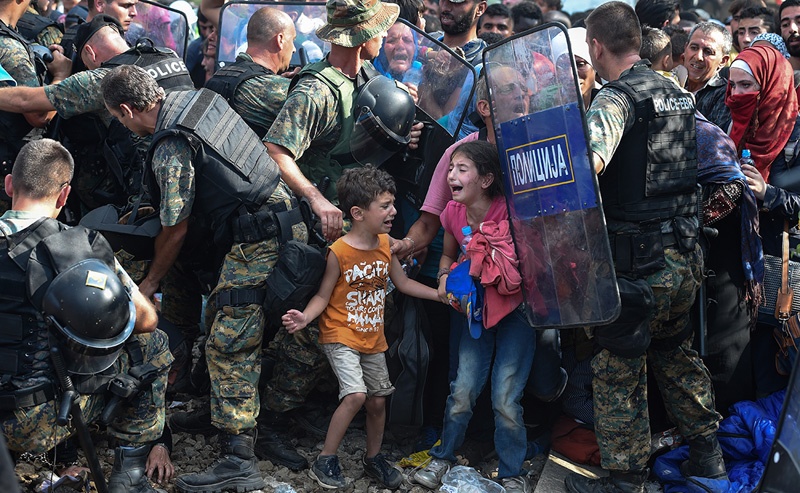 Weinend stehen zwei Kinder, die zwischen vordringenden Menschenmassen und Grenztruppen von ihren Eltern getrennt wurden, an der griechisch-mazedonischen Grenze.