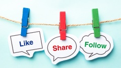 Schilder mit der Aufschrift "like", "share" und "follow" sind mit farbigen Wäscheklammern an einer Schnur festgeklemmt.