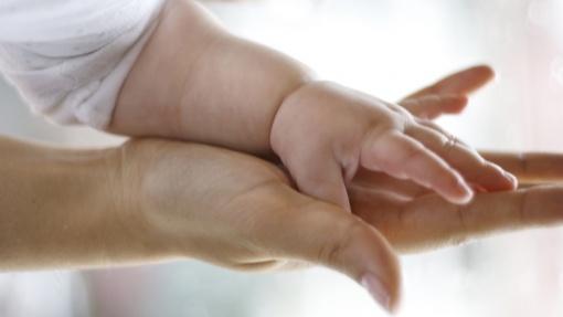 Die Hand eines Babys liegt auf der Hand eines Erwachsenen.