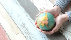 Kleiner Globus liegt in zwei Händen.