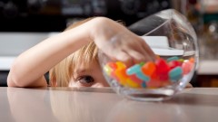Ein Junge greift in ein Glas mit Süßigkeiten.