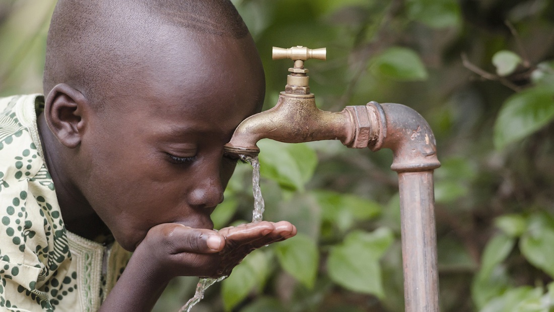 Afrikanischer Junge trinkt sauberes Trinkwasser