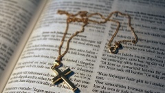 Goldene Kette mit Kreuz-Anhänger auf einer Bibel in schwedischer Sprache.