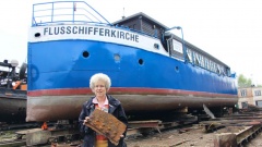 Die Hamburger Flussschifferkirche schwimmt nicht mehr. Christiane Hey-Laib, Vorsitzende des Fördervereins, zeigt ein Stück des durchgerosteten Rumpfes.