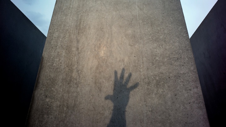 Schatten einer in die Höhe gestreckten Hand auf einer Stele des Holocaust-Mahnmals in Berlin.
