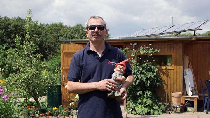 Necati Cavdar steht mit einem Gartenzwerg in der Hand in seiner Parzelle im Frankfurter Kleingartenverein.