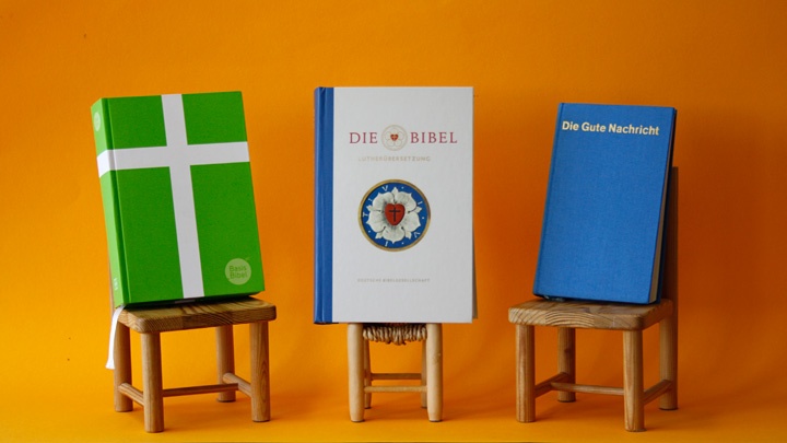 Drei Bibeln auf kleinen Stühlchen, in der Mitte die Lutherbibel 2017.