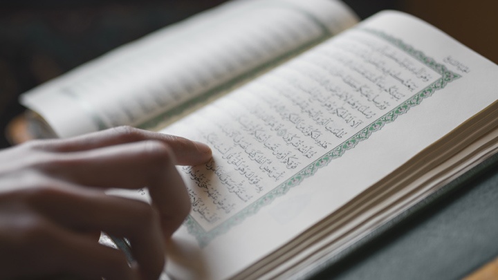 Eine Hand führt über die Seiten des Koran