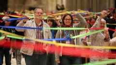 Als Zeichen ökumenischer Brücken verbinden die Teilnehmer des ökumenischen Gottesdienstes beim Katholikentag 2014 farbige Bänder miteinander. 