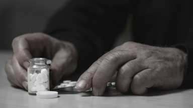 Eine tödliche Dosis Tabletten liegt auf einem Tisch vor einem Mann.