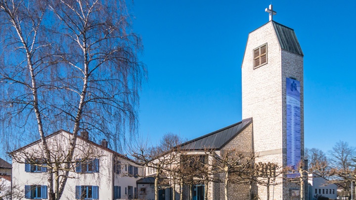 Die  Apostelkirche in Neuburg mit Pfarrhaus und dem Spendenbanner für das neue Gemeindehaus.