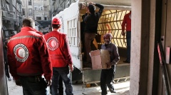 Freiwillige des Roten Halbmondes entladen einen UN-Hilfskonvoi.