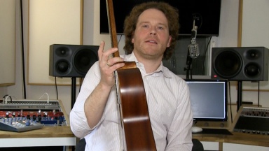 Tim Linde im Studio mit einer Gitarre in der rechten Hand.
