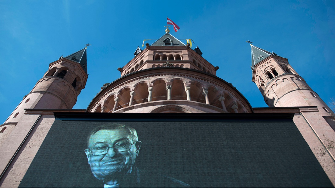 Vor dem Mainzer Dom ist am Mittwoch auf einer Videoleinwand ein Porträt des verstorbenen Kardinals Karl Lehmann zu sehen.